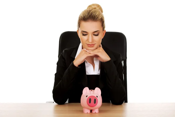 Businesswoman with a piggybank behind the desk — Stock Photo, Image