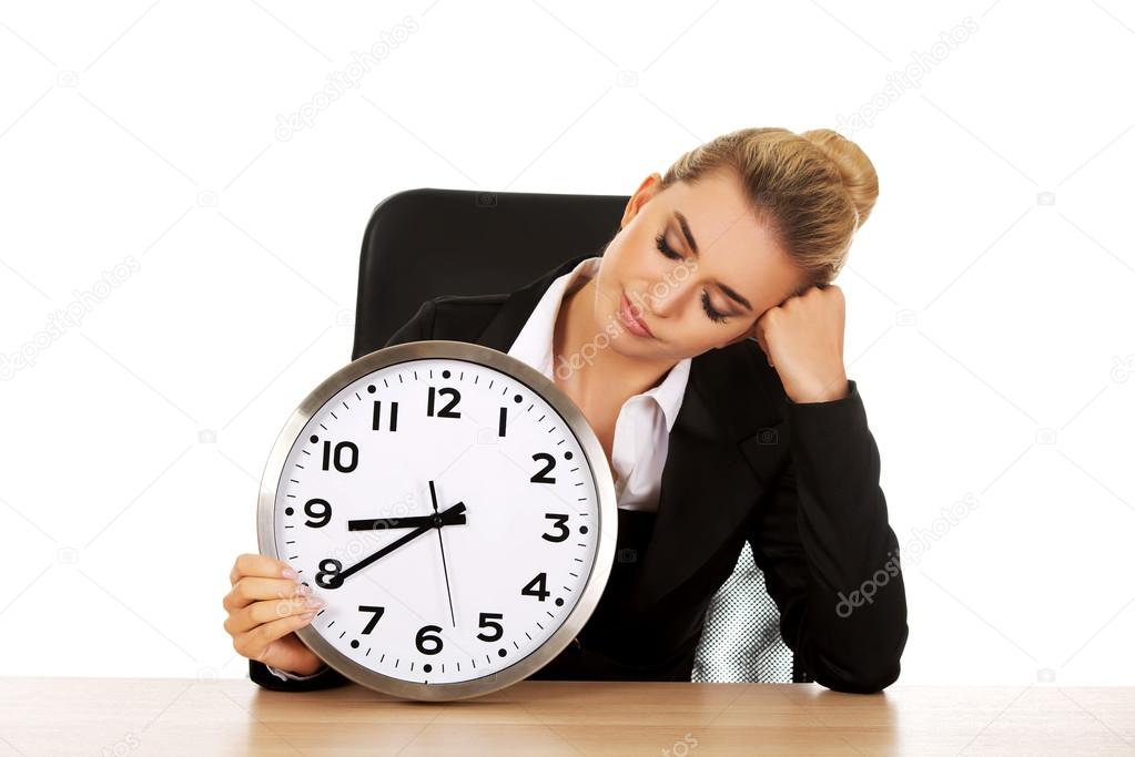 Yawning businesswoman with a clock