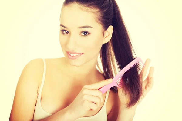 Beautiful woman combs her hair. — Stock Photo, Image