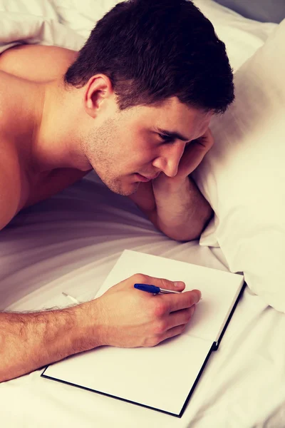 彼のベッドでメモを書いているその男. — ストック写真