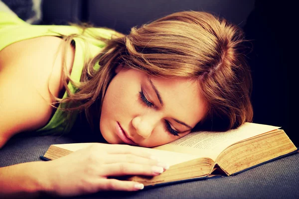 Trött kvinna med hennes huvud på bok. — Stockfoto