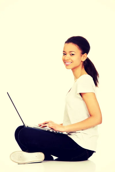 Adolescente sentado de pernas cruzadas com laptop . — Fotografia de Stock