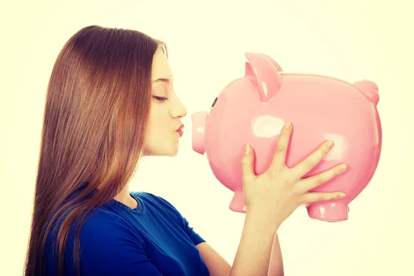 Teenage vrouw kussen spaarpot. — Stockfoto