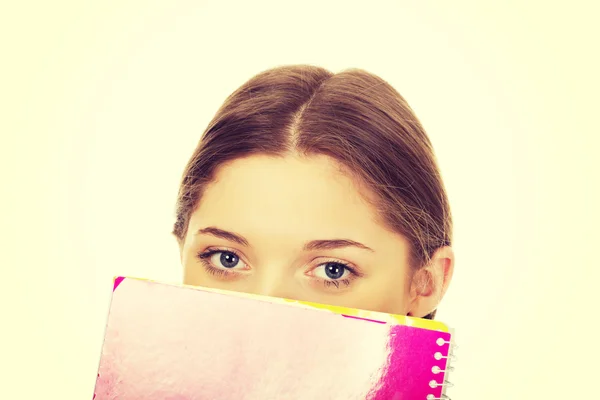 Έφηβος γυναίκα που κρύβεται πίσω από ένα σημειωματάριο. — Φωτογραφία Αρχείου