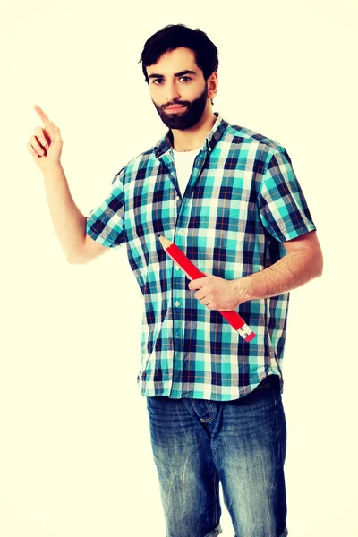 Joven sosteniendo un gran lápiz rojo . — Foto de Stock