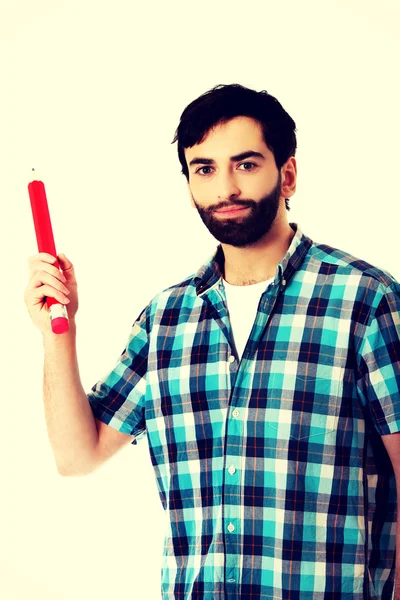 Młody człowiek wskazującego z wielkim czerwonym ołówkiem. — Zdjęcie stockowe