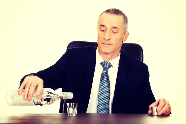 Homme d'affaires au bureau versant de la vodka dans un verre — Photo