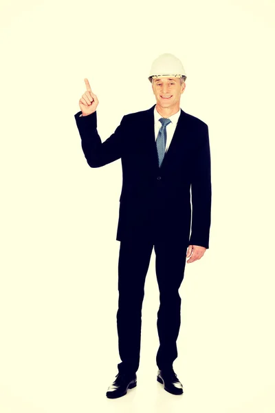 Hombre de negocios sonriente con el sombrero duro apuntando hacia arriba — Foto de Stock
