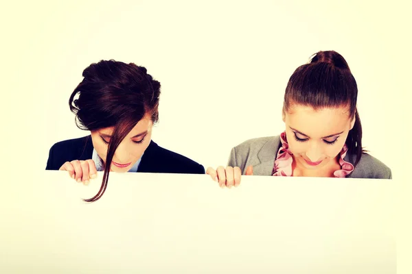 Two businesswomen carrying a big white board. — Stock Photo, Image