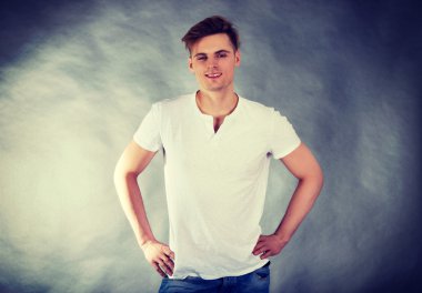 kalça elleri ile genç gülümseyen adam.