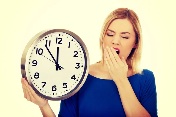 Tired woman holding a clock. — Stock Photo, Image