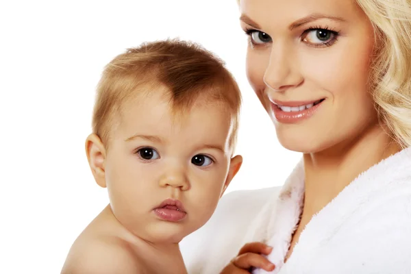 Молодая улыбающаяся мать в халате держит своего ребенка — стоковое фото