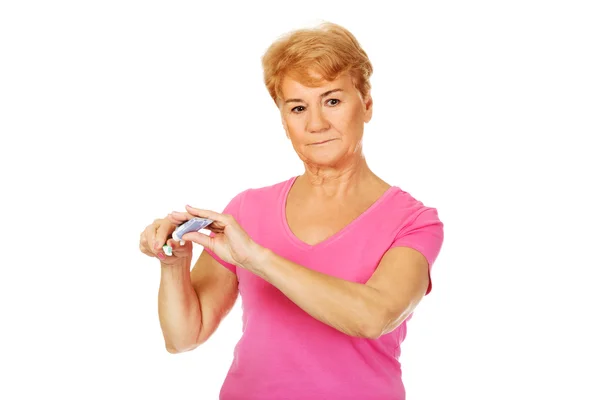 Smiling senior woman holding toothpaste and toothbrush — Stock Photo, Image