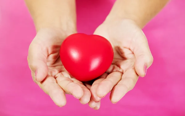 Old woman holding red toy heart — Stock Photo, Image