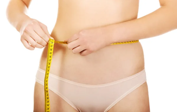 Mujer en forma que mide su cintura con una cinta métrica —  Fotos de Stock
