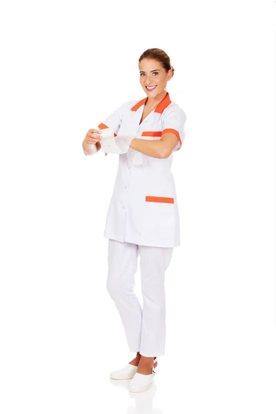 Ung kvinnlig sjuksköterska eller läkare som innehar ett bandage — Stockfoto