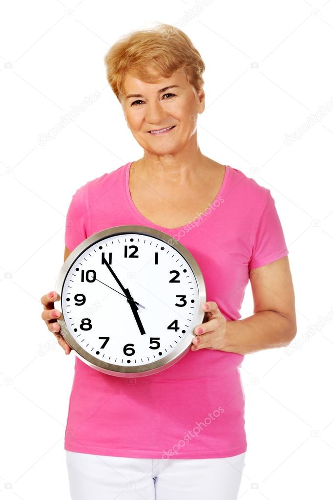 Smiling senior woman holding a clock