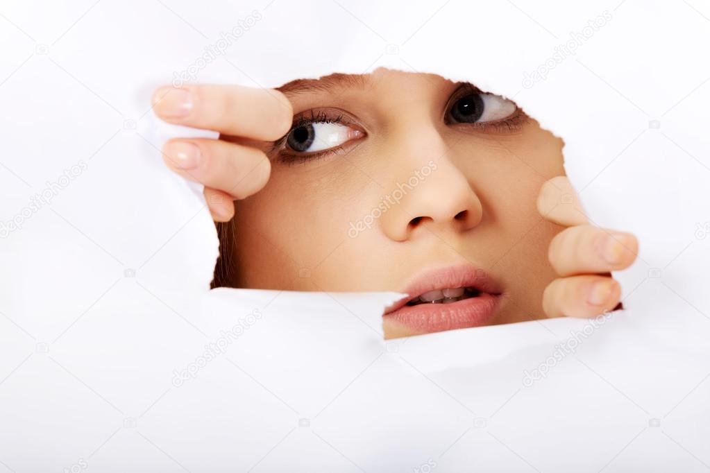 Teenage woman peeping through hole on paper