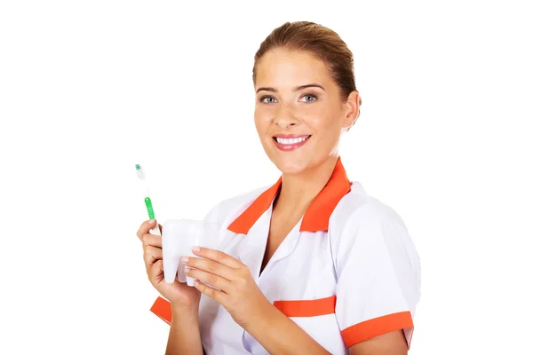 Mujer dentista joven con cepillo de dientes y modelo de dientes —  Fotos de Stock
