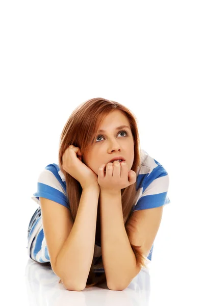 Pensive teenage woman lying on the floor Royalty Free Stock Images