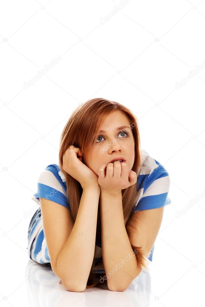 Pensive teenage woman lying on the floor