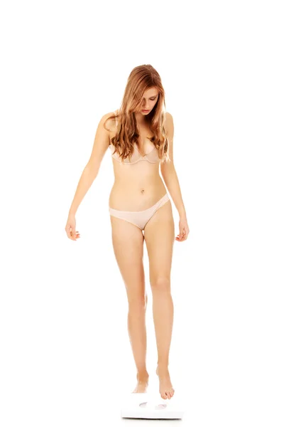 Молодая женщина в нижнем белье стоит на весах — стоковое фото