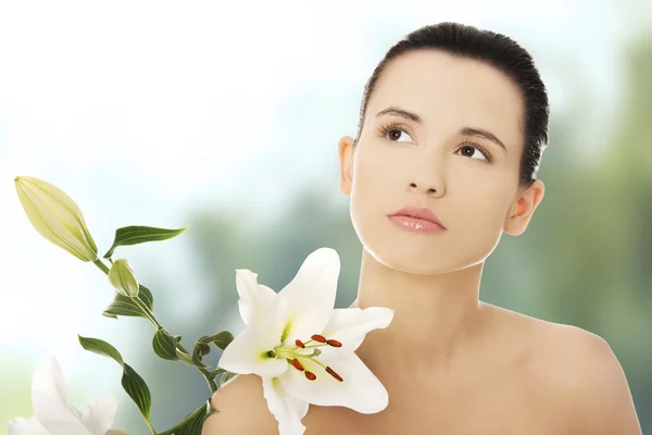 Frau mit gesunder Haut und Lilienblüte — Stockfoto