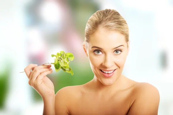 Smiling nude woman holding a fork with lettuce — Stock Photo, Image