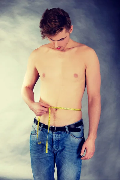 Junger Mann misst Taille. — Stockfoto