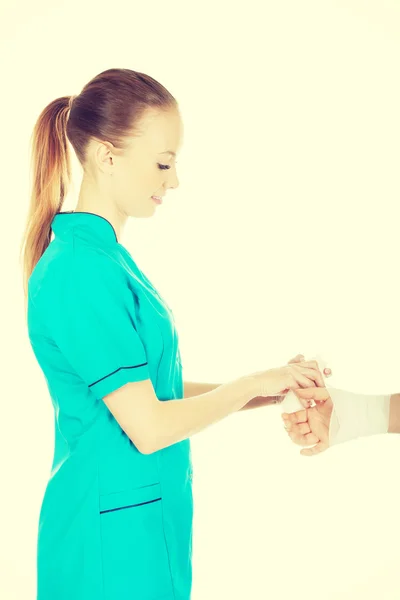 Doktor žena bandážování ženské ruky. — Stock fotografie