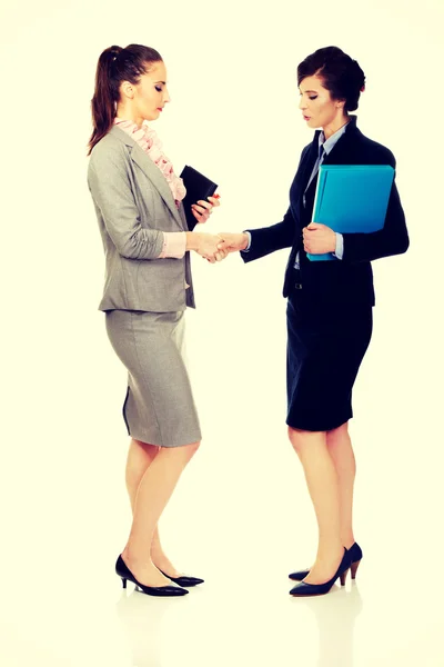 Dvě ženy s notebooky dávat handshake. — Stock fotografie