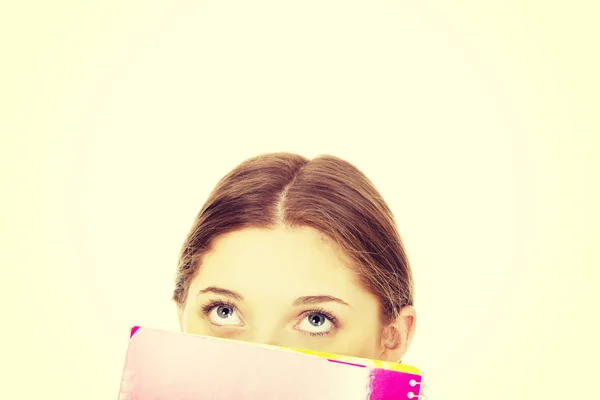 Mujer adolescente escondida detrás de un cuaderno . — Foto de Stock