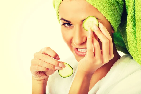 Woman in bathrobe applying cucumber on eyes — Stock Photo, Image