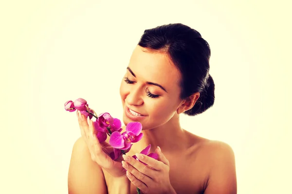 Женщина топлесс с фиолетовой ветвью орхидеи — стоковое фото