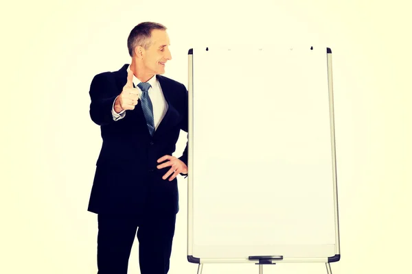 Executivo masculino com ok sinal perto de flip chart — Fotografia de Stock