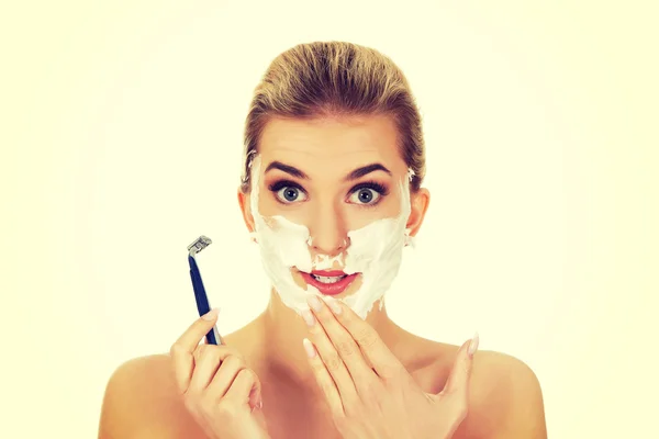 Joven mujer sorprendida afeitándose la cara con una navaja de afeitar — Foto de Stock