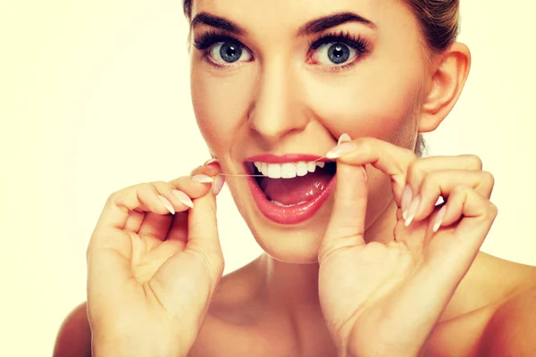 Jovem mulher usando fio dental nos dentes . — Fotografia de Stock