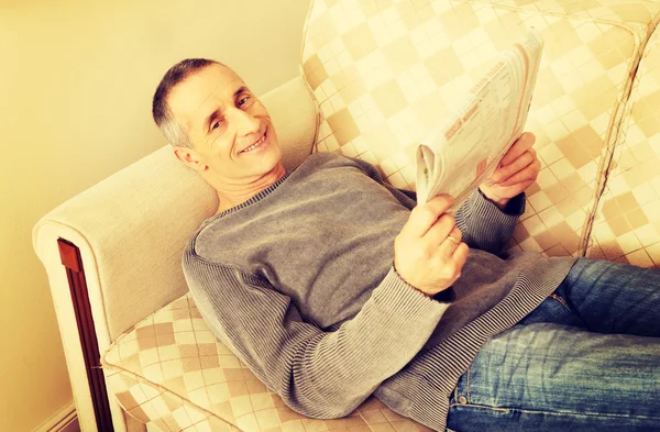 Мужчина средних лет читает дома газету — стоковое фото