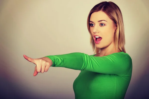 Shocked woman pointing aside. — Stock Photo, Image