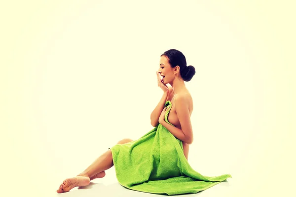Mujer sonriente sentada envuelta en toalla — Foto de Stock
