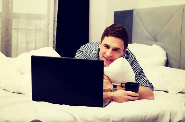 Evdeki yatakta dizüstü bilgisayar kullanan sıradan bir genç.. — Stok fotoğraf
