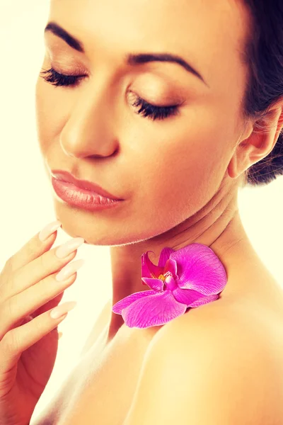 Kvinna med lila orkidé kronblad på axel — Stockfoto