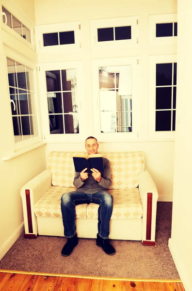 Olgun adam evde kitap okurken — Stok fotoğraf