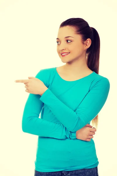 Smiling young woman pointing aside. — Stock Photo, Image
