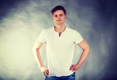 kalça elleri ile genç gülümseyen adam.