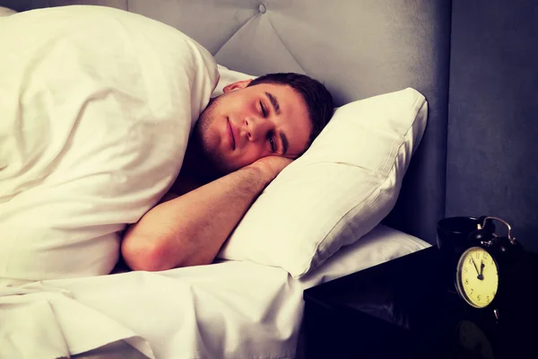 Красивый молодой человек лежит в постели. — стоковое фото