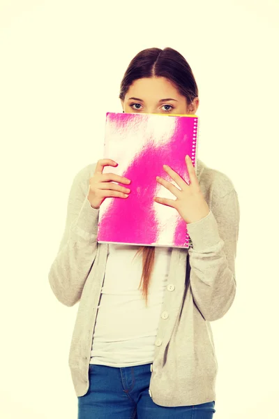 Teen woman hiding behind a notebook. — Stock Photo, Image