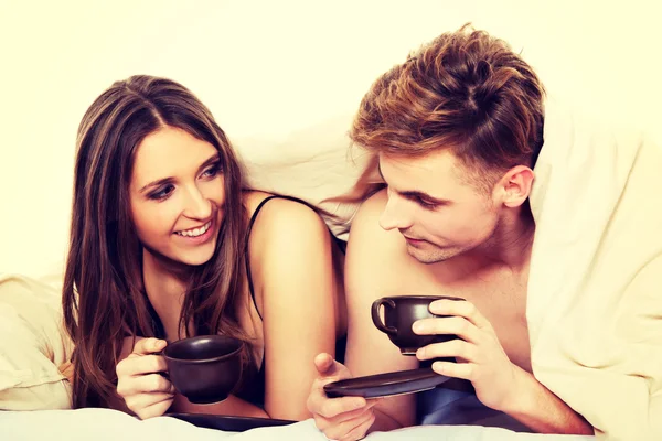 Casal feliz beber café na cama . — Fotografia de Stock