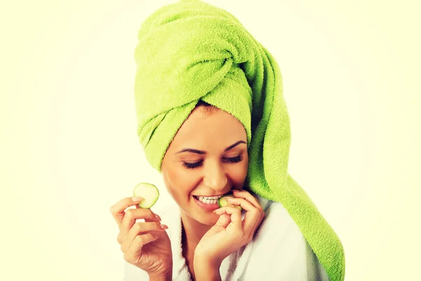 Woman in bathrobe eating cucumber — Stock Photo, Image