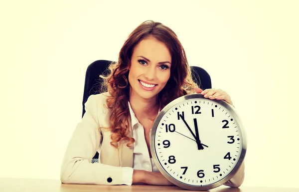 Zakenvrouw met klok door een bureau. — Stockfoto